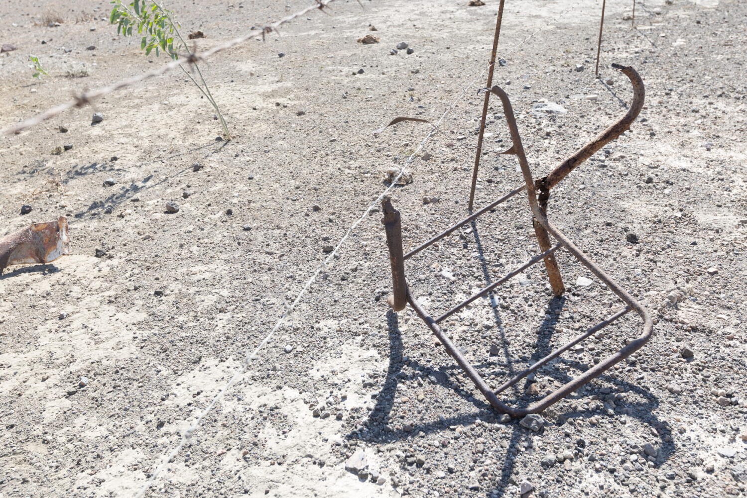 Skeleton of a chair leaning against barbed wire. Fragments of a porcelain mine that has been frozen in time on an island in the Mediterranean.
