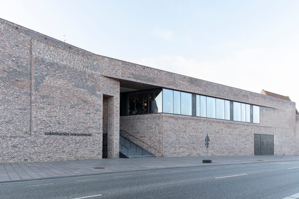 View from the street of the red brick façade and staircase of the European Hanseatic Museum by Andreas Heller Architects in Lubeck.