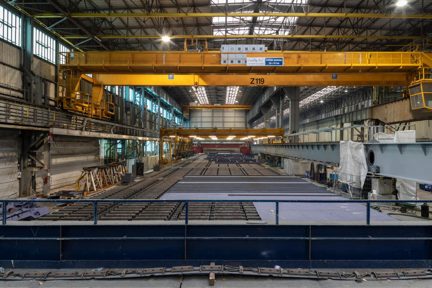Overhead crane transporting metal components at the Fincantieri shipyard in Monfalcone, Italy.