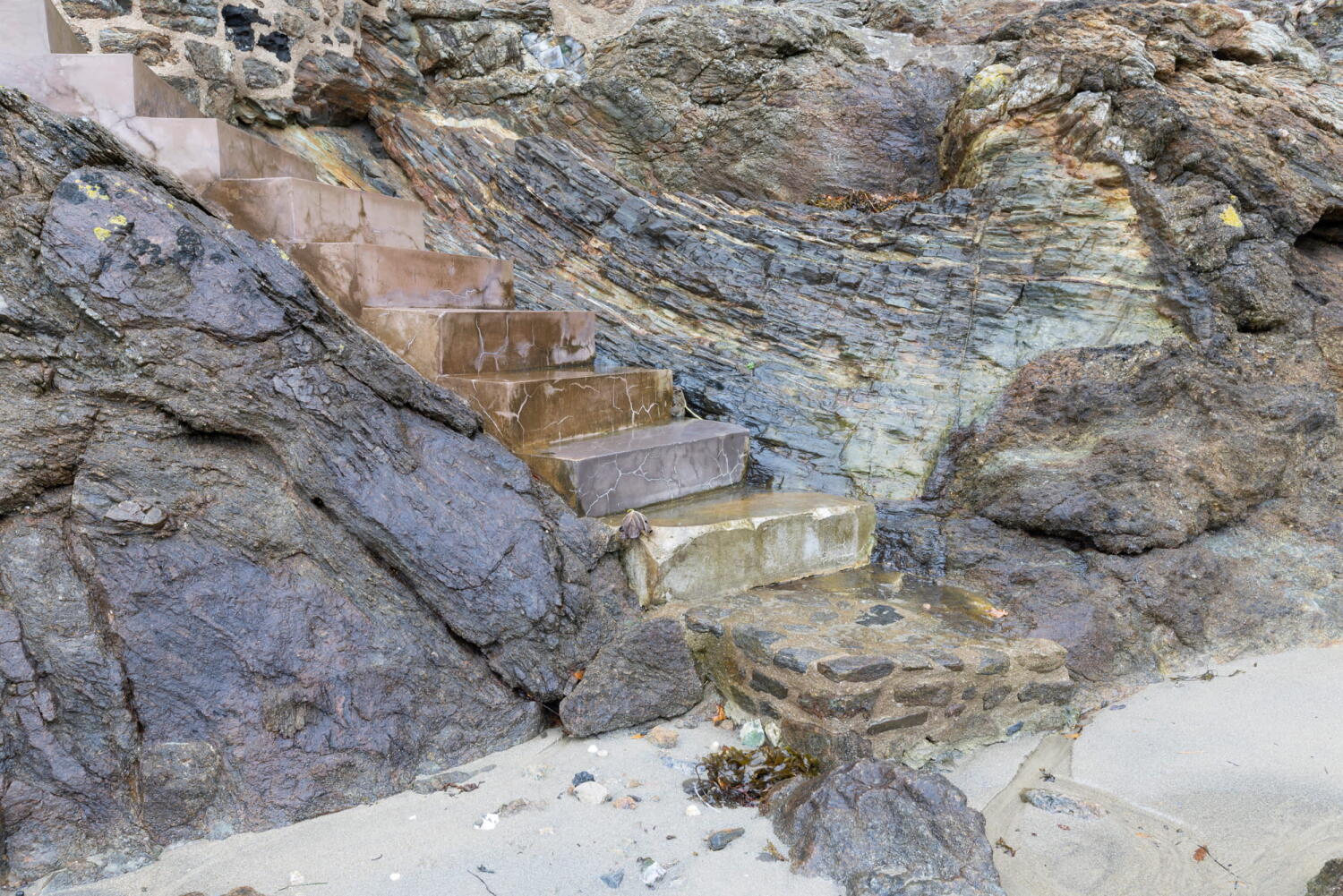 Stairs to the sea on the rocks at the tide line.