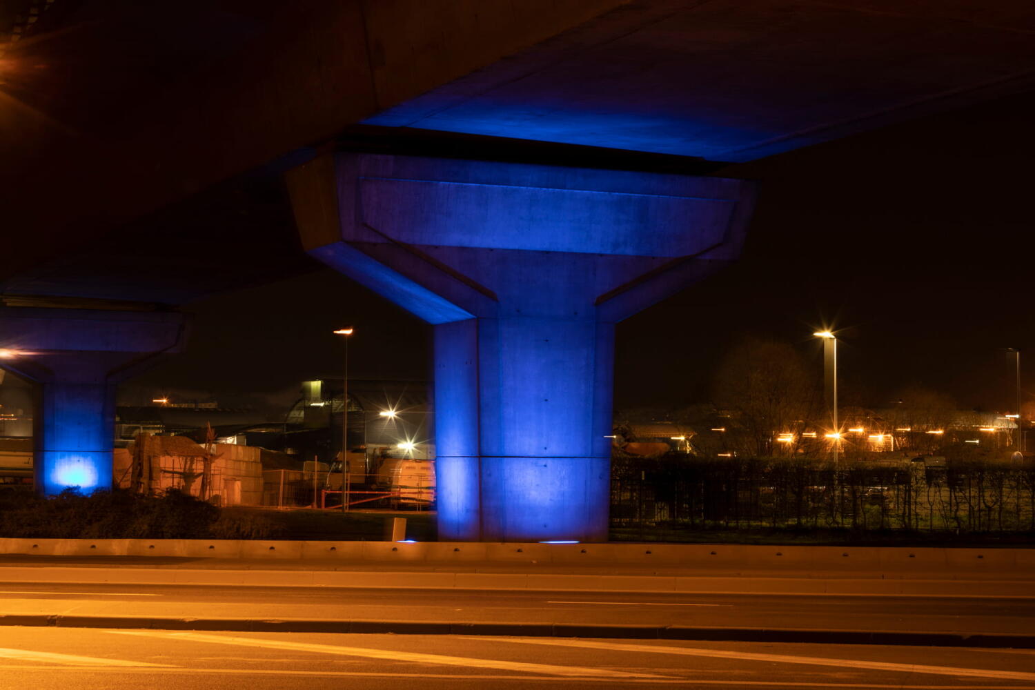 Concrete pillars illuminated by blue light from the series “Night Beasts.” During the night, these industrial structures transform into fantastical creatures that form a bestiary.