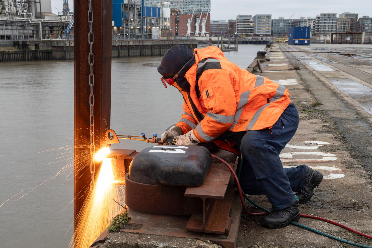 Workers using welding torches on the quay of the Port of Hamburg.