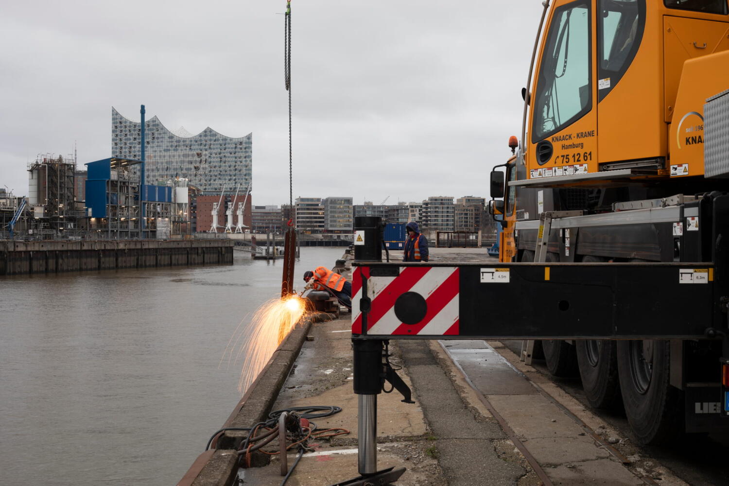 Workers using welding torches on the quay of the Port of Hamburg.